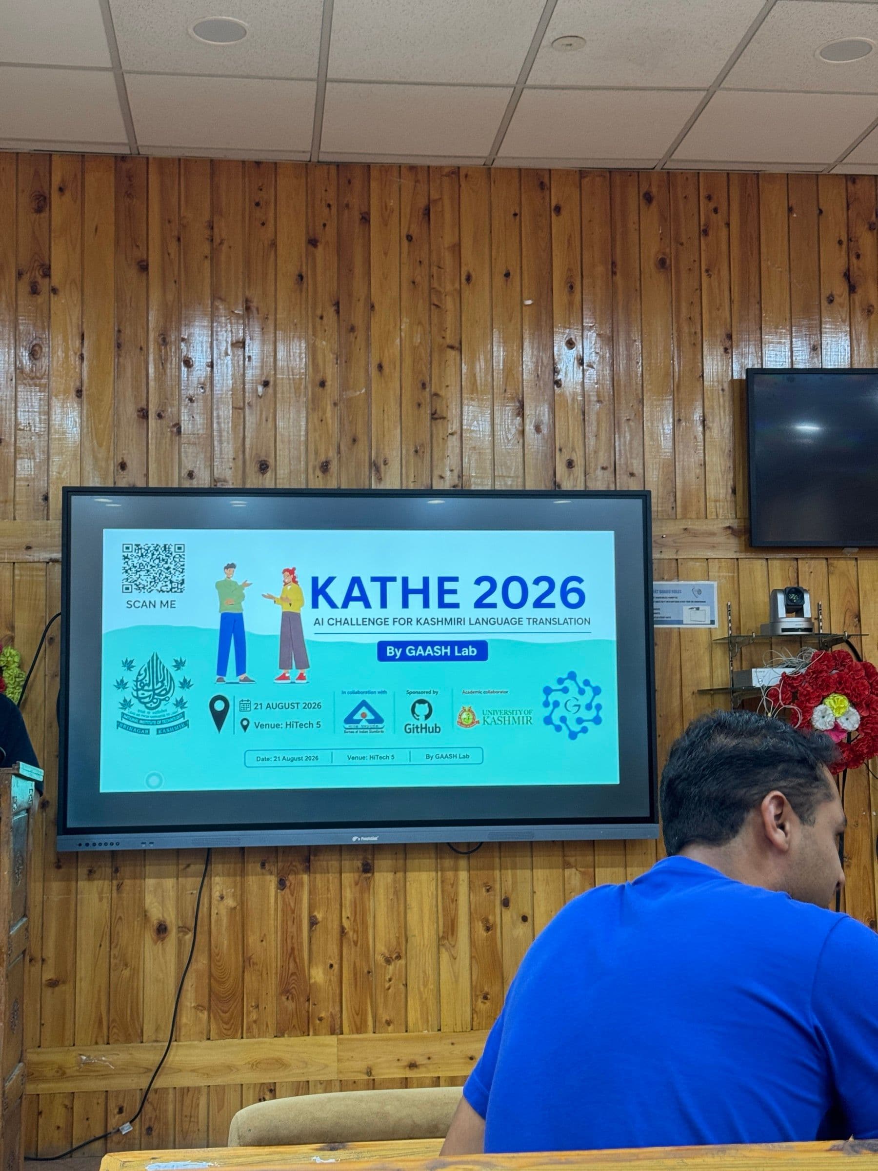 The KATHE 2026 event poster on a display screen: 'AI Challenge for Kashmiri Language Translation', by GAASH Lab